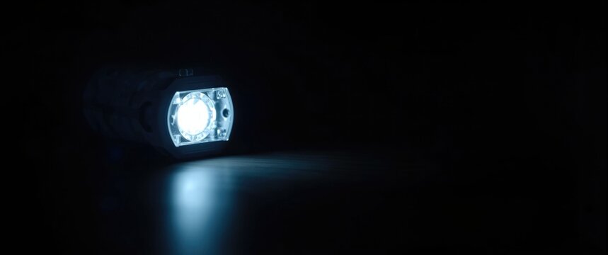 LED Flashlight Illuminating Surface with Blue Light in Dark Setting