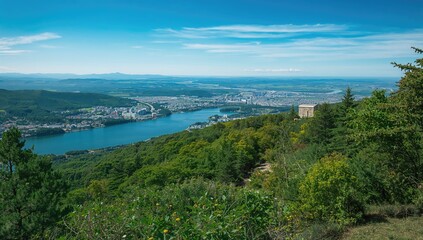 Fototapeta premium Panoramic View of City and River from Hilltop - Clear Blue Sky, Lush Greenery
