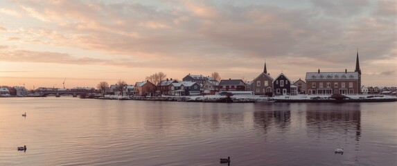 Naklejka premium Snowy Village Reflection on Calm Water at Sunrise with Pastel Sky