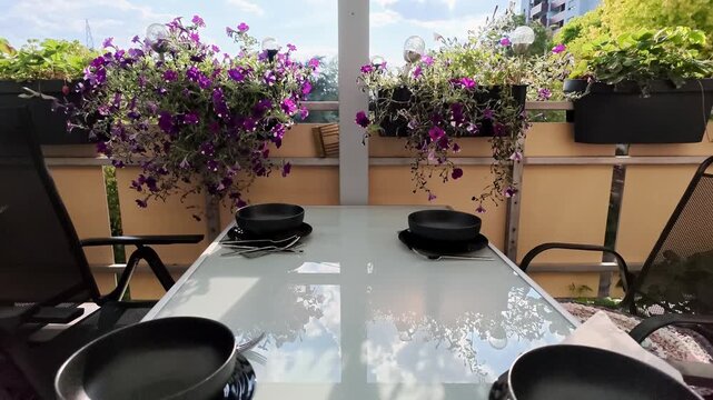 A serene urban balcony scene featuring an outdoor kitchen setup with potted plants, a wooden table, and essential cookware. The relaxed atmosphere is enhanced by the vibrant green and earth.