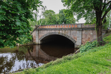 Fototapeta premium Stone arch bridge over Riga City Canal in Bastejkalns Park, Riga, Latvia