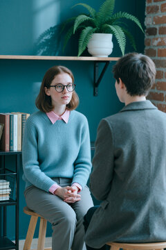 Vertical shot of young adult Caucasian woman listening during counseling session with therapist, discussing mental wellbeing and support. Ideal for therapy, coaching, psychology marketing