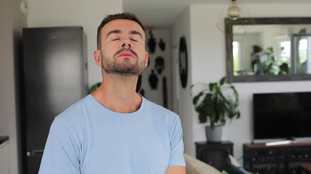 Handsome man closing eyes and breathing mindfully at home alone