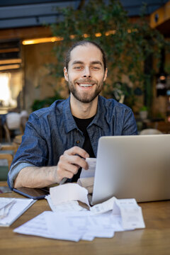 Happy business owner holding receipt near laptop