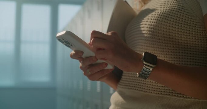 Female Educator Using Smartphone In School Locker Room After Students Have Left. Concept Of Mobile Productivity, Instant Communication, Educational Teamwork, Connected Professionals In Digital Age.
