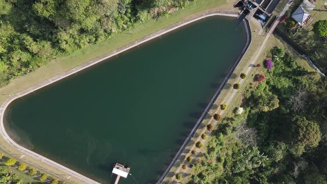 Aerial view of Baturaden reservoir surrounded by lush tropical vegetation and trees in Baturaden, Central Java, Indonesia.