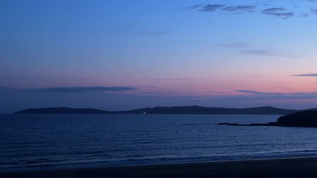 Blue hour twilight over calm sea and silhouetted headland at Sanxenxo beach Galicia Spain
