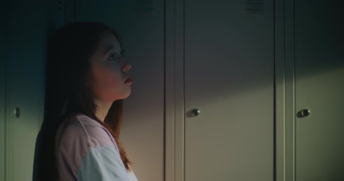 Thoughtful Teenage Schoolgirl Leaning Against Hallway Lockers and Looking Upward While Reflecting After Classes. Concept Of Self Reflection, Emotional Wellbeing, Adolescent Life in Modern High School.