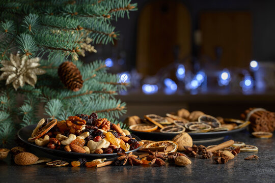 Christmas spices, various nuts, raisins, and dry citrus slices on a kitchen table.