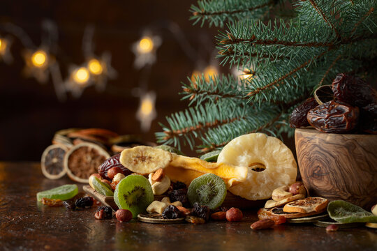 Dried tropical fruits with various nuts and raisins on a old brown table.
