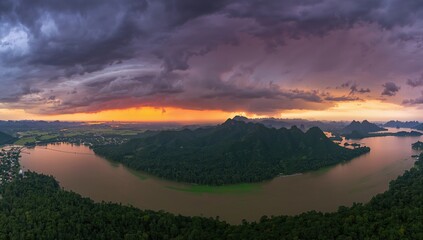 Naklejka premium Majestic Mountain Landscape Overlooking a River at Sunset with Dramatic Clouds