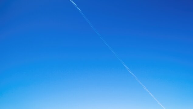 Clear Blue Sky with a Contrail Stretching Across the Horizon