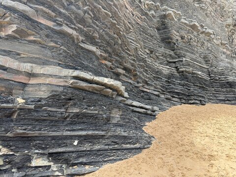 Layered Rock Strata Cliff Face Meeting Sandy Beach