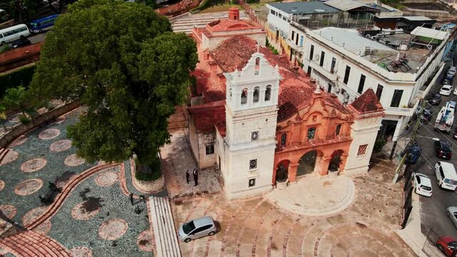 Aerial view of the historic Catedral Castrense de Santa Barbara with its distinctive red roof and bell tower, set within a cobblestone plaza in Santo Domingo, Distrito Nacional, Dominican Republic.