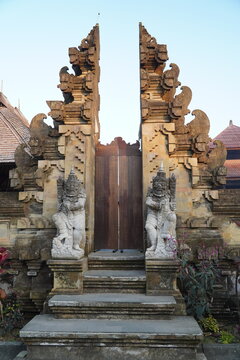Traditional Balinese split temple gate with guardian statues and stone carvings