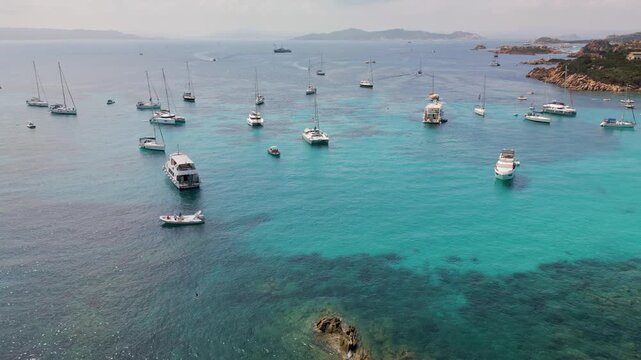 Panoramic view of the turquoise bay with yachts and boats off the coast of Santa Maria Island in the La Maddalena archipelago, Sardinia, Italy