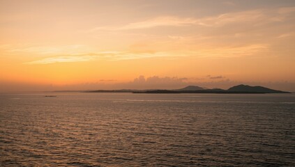 Obraz premium Serene Seascape at Sunset with Gentle Waves and Distant Islands