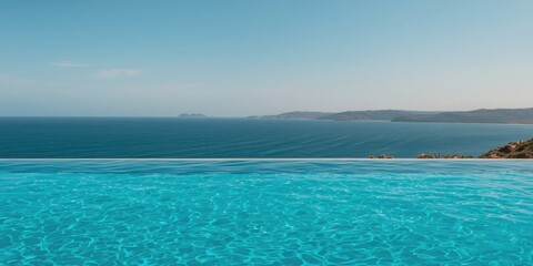 Fototapeta premium Infinity Pool Overlooking a Calm Ocean Under Clear Blue Sky