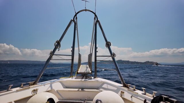 The bow of a boat with a gangplank heading out to sea on a sunny day