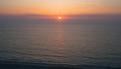 Obraz premium Sunset Over Calm Ocean Waves with Soft Pastel Skies