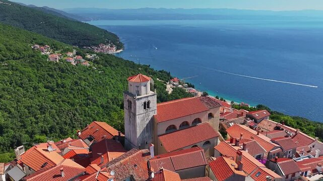 Moscenice, Croatia - 4K flying around of Church of St. Andrew at the medieval village of Moscenice in the municipality of Moscenicka Draga near the Adriatic coast at summertime with red rooftops