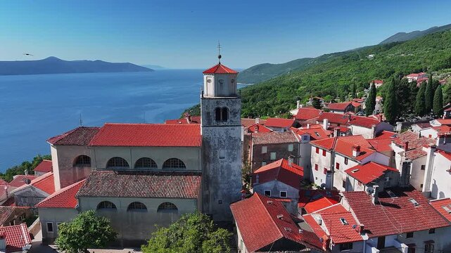 Moscenice, Croatia - 4K flying around of Church of St. Andrew at the medieval village of Moscenice in the municipality of Moscenicka Draga near the Adriatic coast at summertime with red rooftops