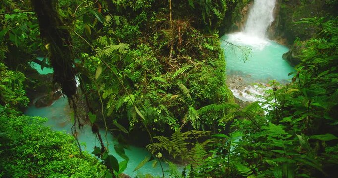 Turquoise river and waterfall flowing through lush dense jungle forest in Costa Rica