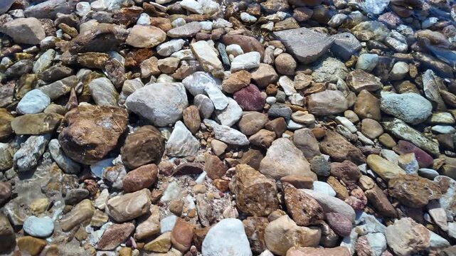 Stones in the crystal clear water of a stream or shallow body of water, viewed from above as a texture or background