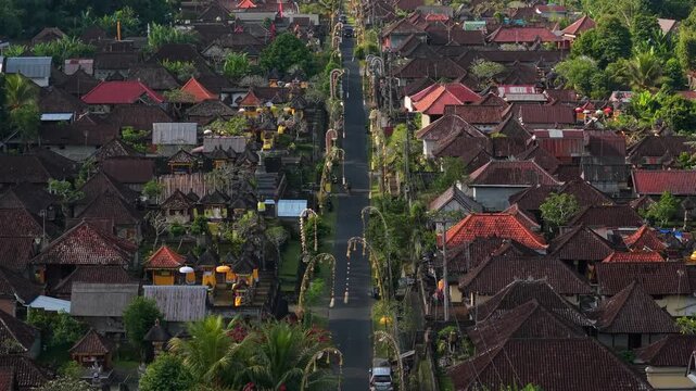 Aerial view of a traditional Balinese village decorated with ornate penjor bamboo poles along the main street in Kecamatan Tegallalang, Bali, Indonesia.
