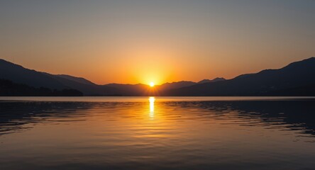 Obraz premium Sunrise Over Calm Lake With Mountain Silhouettes and Reflective Water
