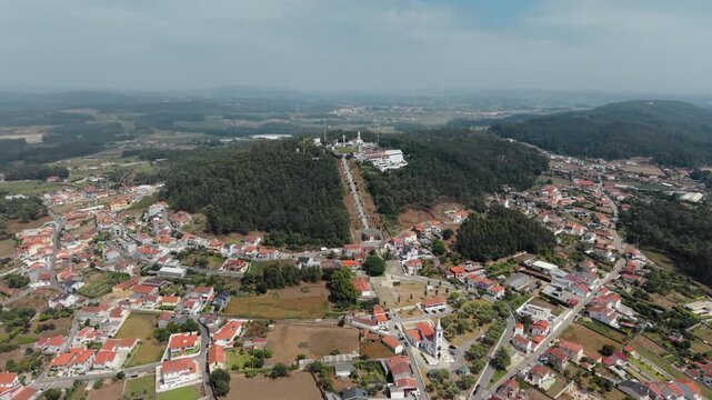 Aerial view of Capela de Sao Felix and Santuario da Senhora da Saude de Laundos surrounded by lush forests and residential houses in Laundos, Porto, Portugal.