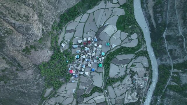 Aerial view of traditional Himalayan village with colorful roofs and farm terraces near Jispa Lahaul Valley shot by a drone
