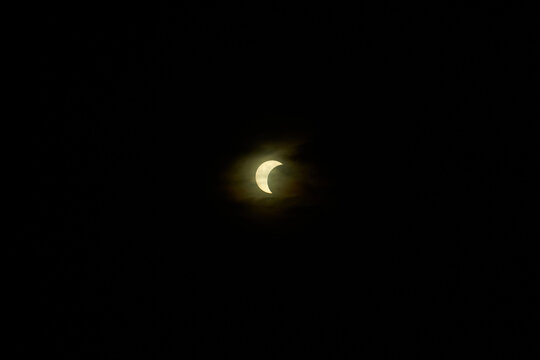 Solar eclipse creating crescent sun shape in dark sky
