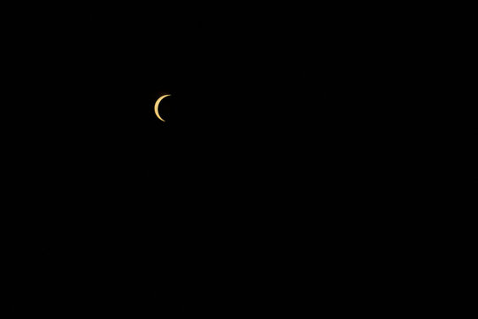 Partial solar eclipse showing sun crescent in dark sky