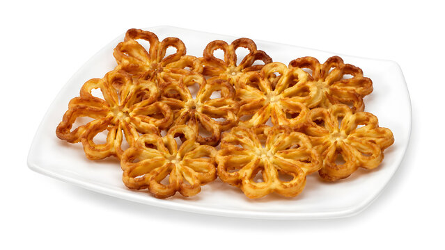 Flower shaped golden brown honeycomb cookies stacked on a white ceramic plate isolated on white background