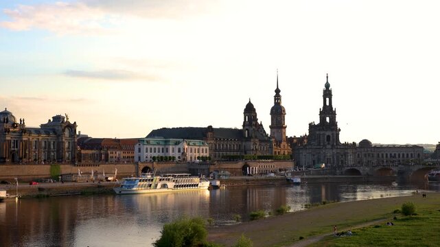 Scenic warm sunset beautiful Dresden city skyline at Elbe River with many steam tourist ship vessel moored at bank. Saxony Germany capital cityscape dusk panorama view with old Europe architecture