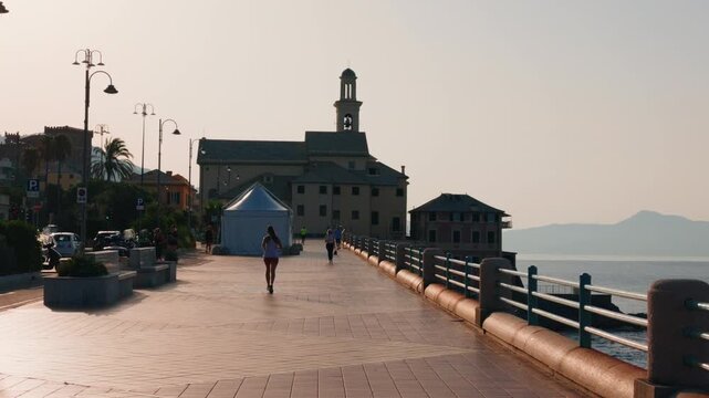 People jogging along seaside promenade with historic church and morning light