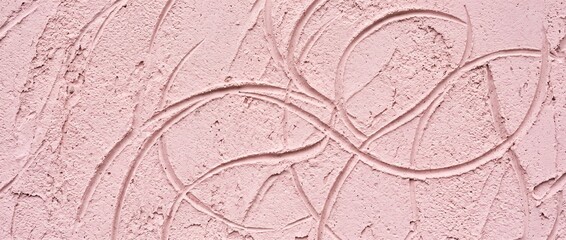 Fototapeta premium Macro close-up of a soft pastel pink plaster wall surface featuring intricate swirling hand-drawn texture patterns and artisanal finish