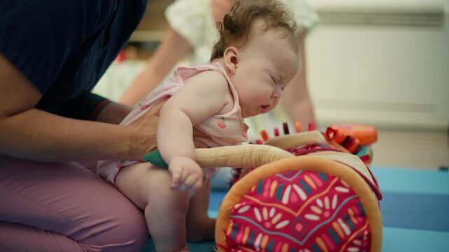 Infant with a pacifier getting physical therapy from a professional, improving gross motor skills and development