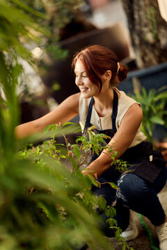 Smiling Woman Gardening in Nursery Potting Plants for Small Business and Lifestyle Branding