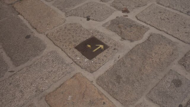 Camino de Santiago plaque with scallop shell and yellow arrow set in granite paving
