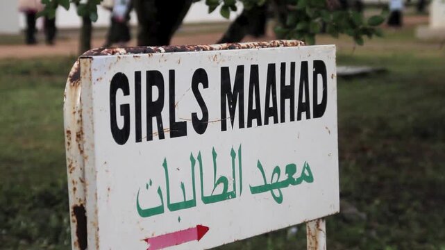 A sign for a girls maahad school with english and arabic text