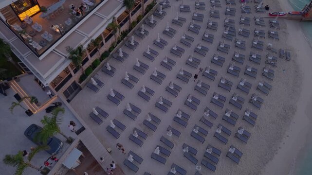 Aerial view of a beach club with rows of sun loungers and umbrellas on the sandy shore in Ksamil, Vlore County, Albania.