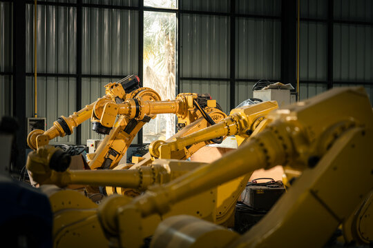 Industrial Automation Equipment with Multiple Yellow Robot Arms Arranged inside a Manufacturing Workshop