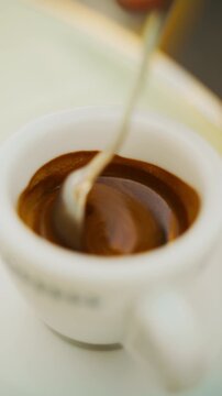 A teaspoon stirs in a cup of Italian coffee on the island of Capri at a bar