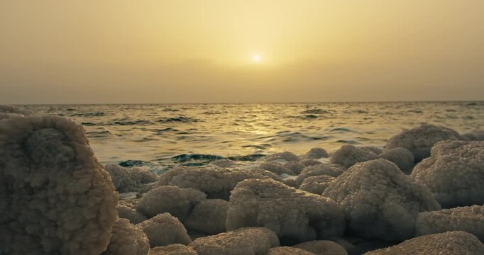 Sunset over Dead Sea salt formations in Jordan with gentle waves, golden light, and a peaceful hypersaline shoreline.
