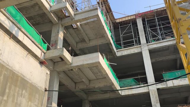Low angle shot of a reinforced concrete cantilever beam supporting a floor slab. Structural view within an active modern building construction site.
