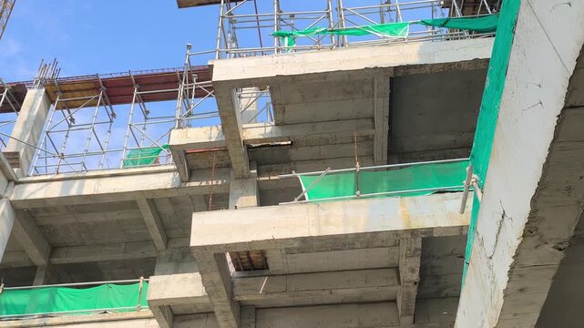 Low angle shot of a reinforced concrete cantilever beam supporting a floor slab. Structural view within an active modern building construction site.