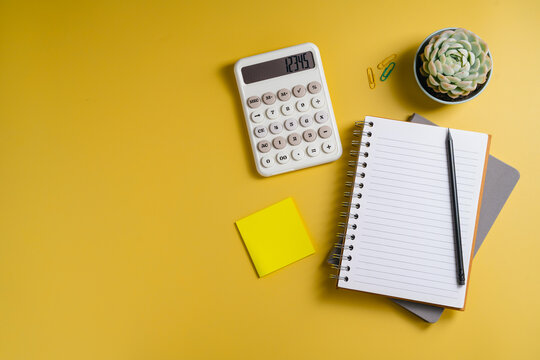 Personal financial planning with calculator, notebook and sticky note on yellow background, flat lay with copy space