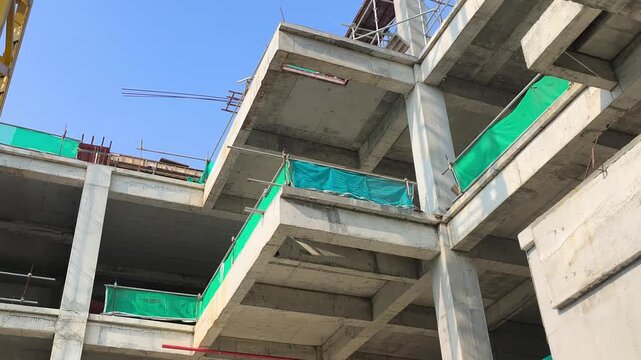 Low angle shot of a reinforced concrete cantilever beam supporting a floor slab. Structural view within an active modern building construction site.